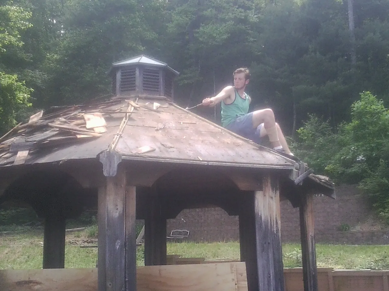 Tearing the old roof off a wooden gazebo before new shakes in Albion